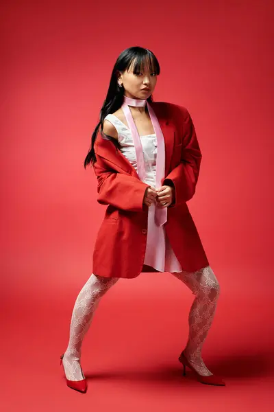 An elegant woman radiates confidence in bold layers and footwear against crimson. — Stock Photo