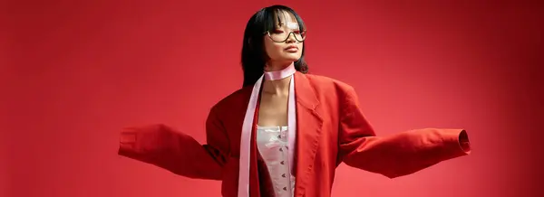 A stunning Asian woman elegantly poses, showcasing her unique style in a vibrant red setting. — Stock Photo
