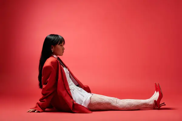 With poised elegance, a woman in a red outfit showcases her unique fashion sense amid vivid colors. — Stock Photo