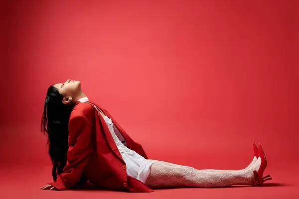 An elegant woman reclines on the floor, exuding confidence with her striking outfit and pose. — Stock Photo