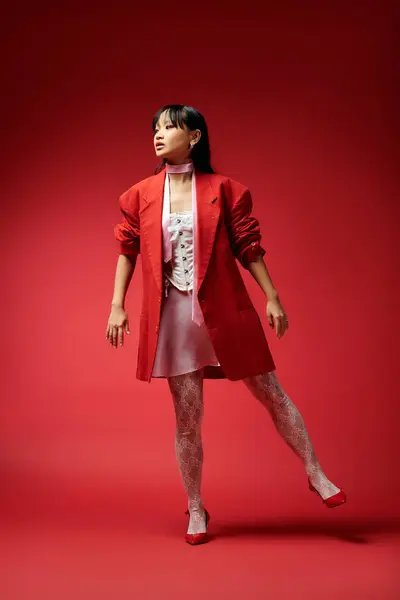 A confident young woman showcases her fashion sense in a stunning red outfit and poses elegantly. — Stock Photo