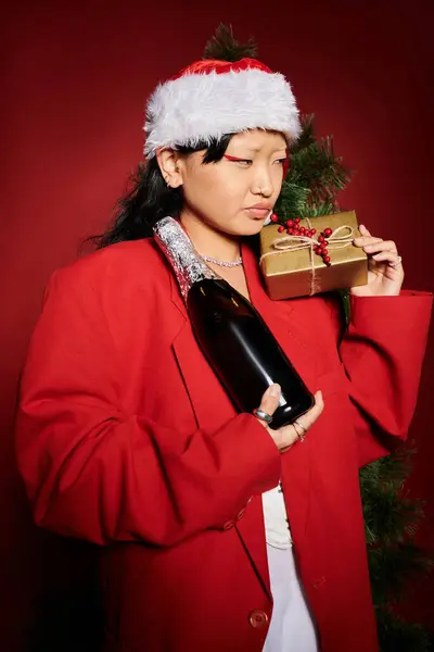 A stylish woman in a festive outfit holds a gift and champagne, radiating holiday cheer. — Stock Photo