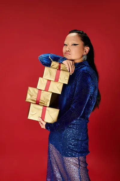 Dressed in a sparkling blue outfit, she showcases elegant gifts with a fierce expression. — Stock Photo