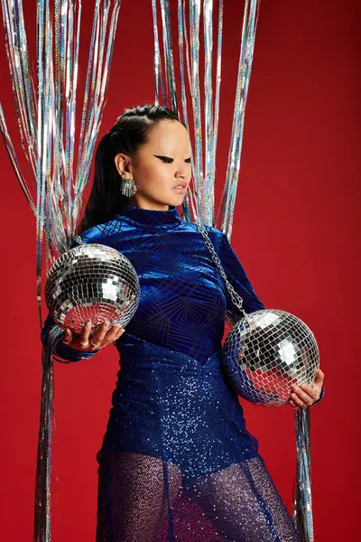 The striking woman showcases her style while holding reflective disco balls with confidence. — Stock Photo