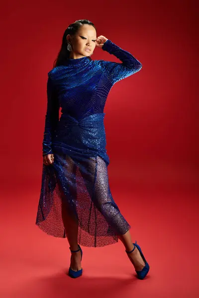 The elegant woman poses confidently, dressed in a sparkling blue outfit, radiating beauty and grace. — Stock Photo
