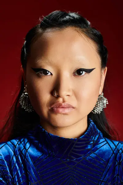 Una mujer elegante emana confianza con delineador audaz y pendientes impresionantes en un entorno dinámico. — Stock Photo