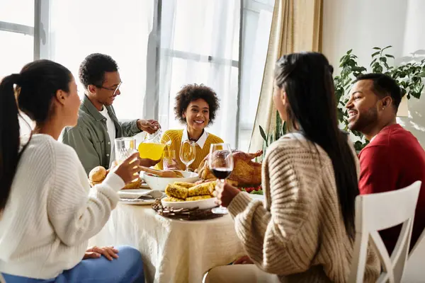 Un gioioso gruppo di amici si riunisce intorno al tavolo, assaporando piatti e bevande del Ringraziamento. — Foto stock