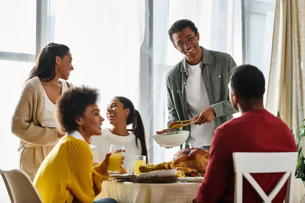Un grupo de amigos celebra Acción de Gracias, disfrutando de la comida y la risa en un ambiente acogedor en casa. - foto de stock