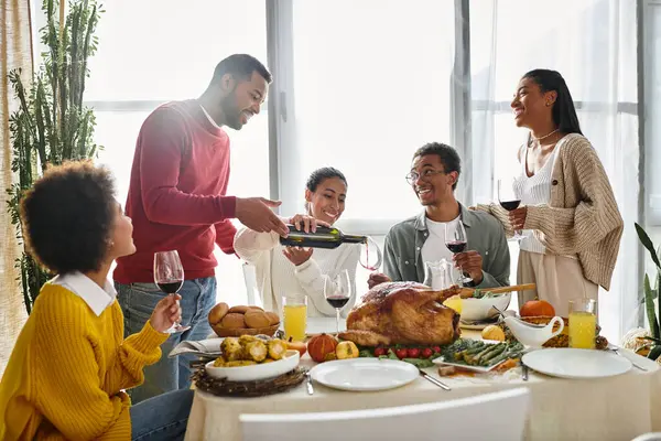 A lively group of friends enjoys their Thanksgiving feast, sharing smiles and toasting together. — Stock Photo