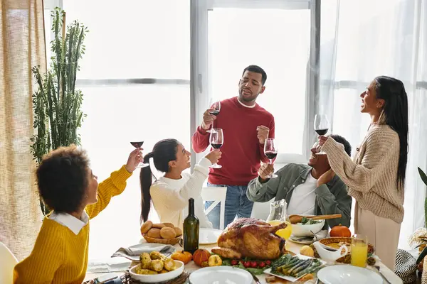 A group of friends raises glasses in a toast while enjoying a Thanksgiving feast together. — Stock Photo