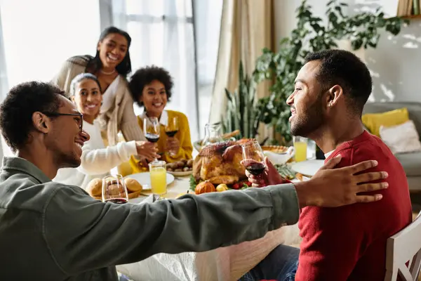A fun group of friends shares food, laughter, and toasts on a warm Thanksgiving. — Stock Photo