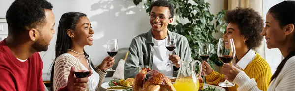 A group of friends shares laughter and toasts while enjoying a Thanksgiving feast together. — Stock Photo