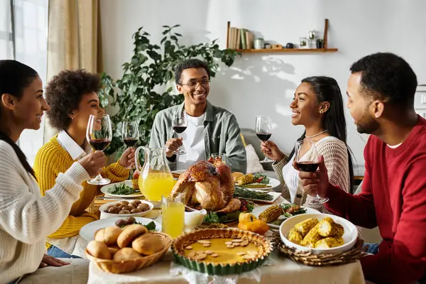 Un gruppo di amici brinda con gli occhiali mentre si gode un pasto festivo del Ringraziamento a casa. — Foto stock