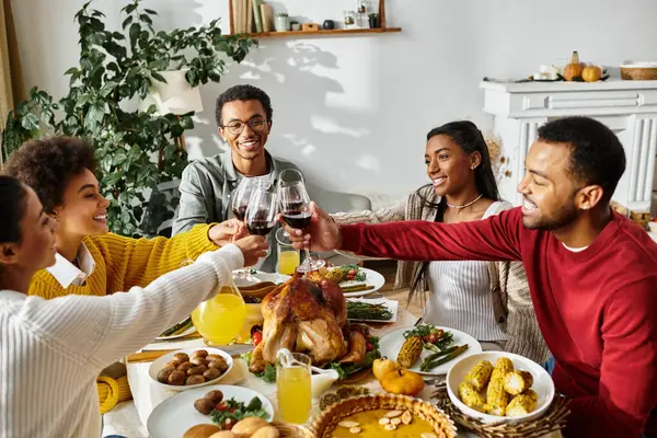 Un grupo de amigos se reúnen alrededor de una mesa bellamente puesta, compartiendo comida e historias en Acción de Gracias. - foto de stock