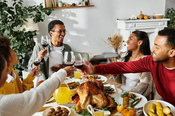 A group of friends raises their glasses in celebration while enjoying a Thanksgiving feast together. — Stock Photo