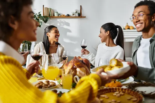 A group of friends shares laughter and a festive meal during their Thanksgiving gathering at home. — Stock Photo