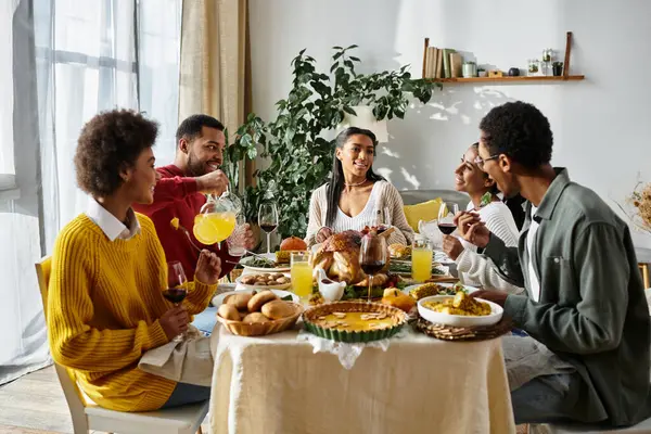 Os amigos desfrutam de uma calorosa reunião de Ação de Graças em casa, compartilhando risos e pratos deliciosos. — Fotografia de Stock