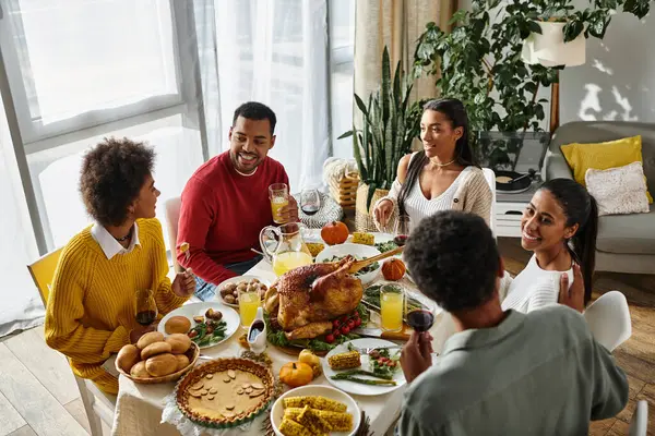 A group of friends shares laughter and delicious food during a cozy Thanksgiving gathering. — Stock Photo