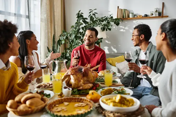 A joyful gathering of friends enjoying a festive Thanksgiving meal with laughter and food. — Stock Photo