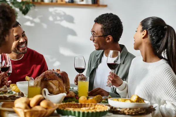 A group of friends shares laughter and delicious food during their Thanksgiving celebration at home. — Stock Photo