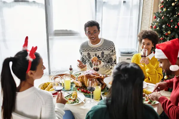 Um encontro alegre de amigos comemorando o Natal com comida e risos em um ambiente acolhedor. — Fotografia de Stock