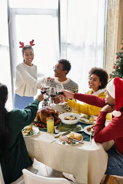 Un allegro raduno di amici che brindano con gli occhiali, condividendo insieme un pasto festivo. — Foto stock