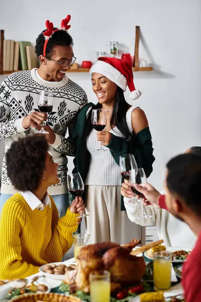 Eine Gruppe von Freunden stößt mit Gläsern in einer warmen, festlichen Atmosphäre auf Weihnachten an. — Stockfoto