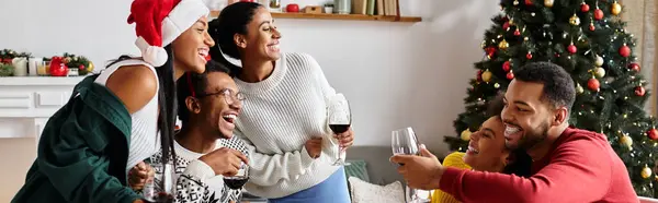 A group of friends shares laughter and drinks in a warmly decorated living room during Christmas. — Stock Photo