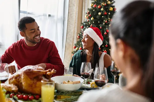 Risa y alegría llenan la sala de estar mientras los amigos comparten una comida festiva durante la Navidad. — Stock Photo