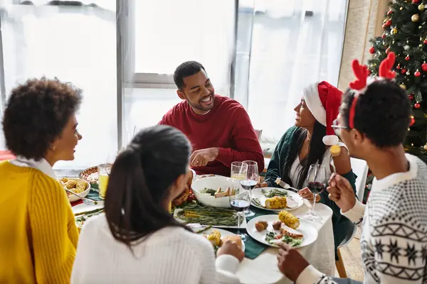 A group of friends gathers around the dining table to enjoy a festive Christmas meal. — Stock Photo
