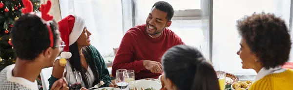 Amigos disfrutando de una comida navideña festiva juntos, compartiendo historias y risas en casa. - foto de stock