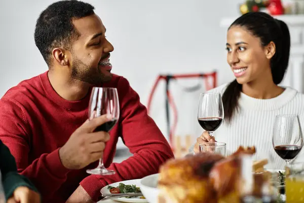 Laughter fills the air as friends toast with glasses of red wine during their Christmas gathering. — Stock Photo