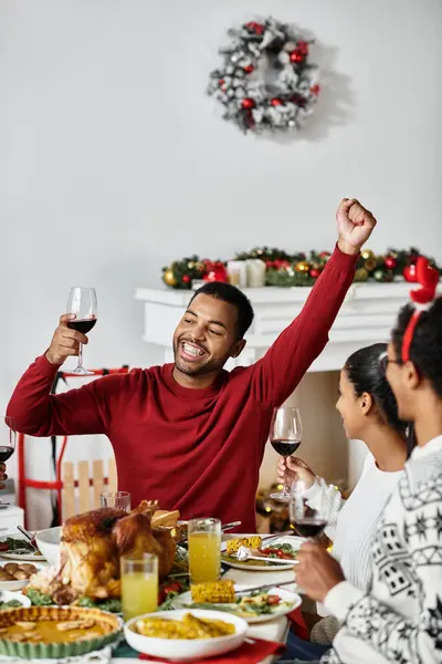 Friends share laughter and toast with drinks while enjoying a festive Christmas feast together. — Stock Photo