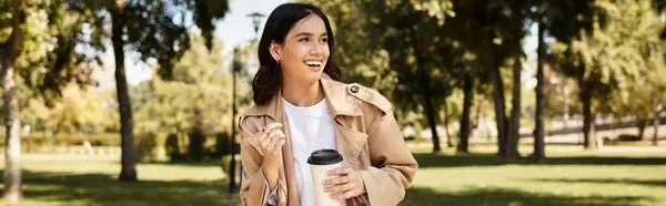 A young woman dressed warmly enjoys a delightful walk in an autumn park, smiling cheerfully. — Stock Photo
