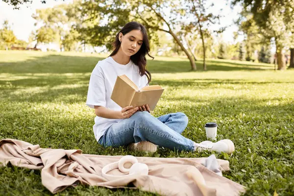 A young woman sits on soft grass, engrossed in a book, surrounded by autumn colors and tranquility. — Stock Photo