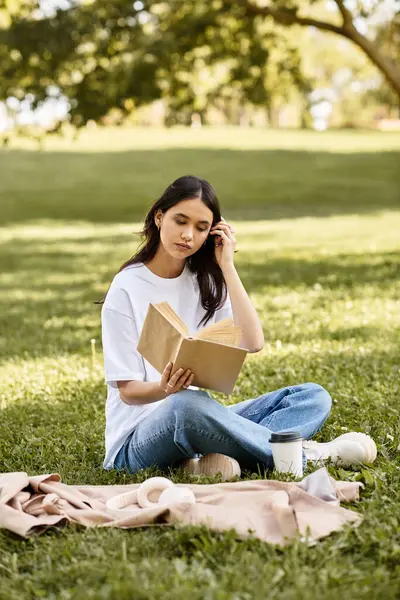 A beautiful young woman sits on the grass, engrossed in her book on a sunny autumn day. — Stock Photo