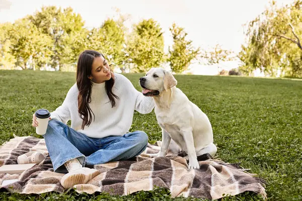 Una giovane donna in caldo abbigliamento autunnale condivide un bel momento con il suo cane su una coperta. — Foto stock