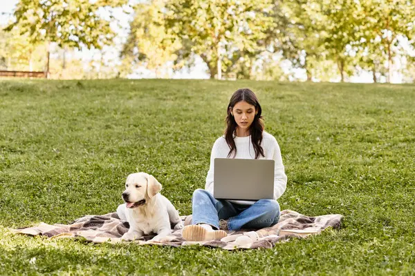 Una giovane donna in accogliente abbigliamento autunnale è concentrata sul suo computer portatile, godendo serenamente il parco. — Foto stock