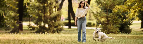 A young woman in warm clothes plays joyfully with her dog amidst the colorful autumn landscape. — Stock Photo