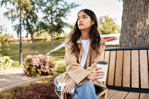 Relaxing in a cozy outfit, a woman savors her drink amidst vibrant autumn foliage. — Stock Photo