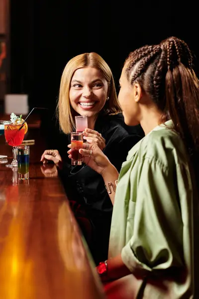 Two diverse colleagues share drinks and joyful moments at a corporate celebration event. — Stock Photo