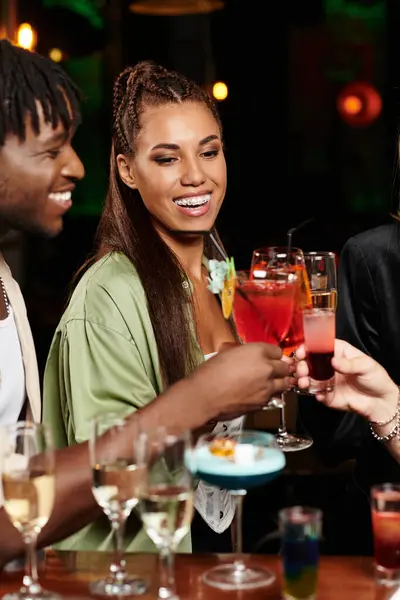Young diverse professionals celebrate with colorful cocktails at a festive corporate gathering. — Stock Photo