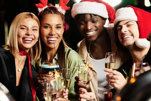 Cheerful young professionals share a joyful moment, raising glasses at a holiday celebration. — Stock Photo