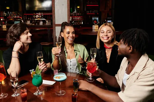 Four colleagues enjoy drinks and laughter at a lively corporate gathering, enhancing team spirit. — Stock Photo