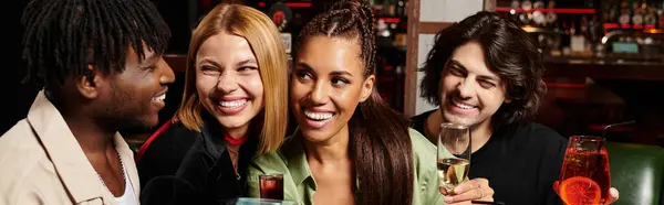 A lively gathering of young professionals enjoying drinks and laughter at a corporate celebration. — Stock Photo