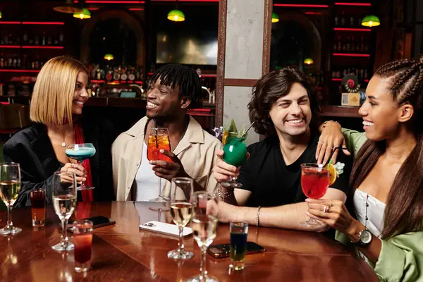 Colleagues share joyful moments while sipping colorful cocktails in a lively atmosphere. — Stock Photo