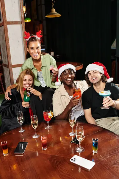Vier Kollegen stoßen bei festlichem Beisammensein mit bunten Cocktails auf die Feiertage an. — Stockfoto