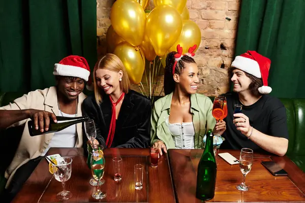 Four young professionals share laughter and festive drinks, celebrating together at a party. — Stock Photo