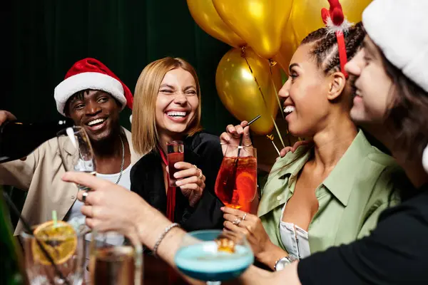 Um grupo animado de colegas diversos gosta de bebidas e risos em uma celebração de férias. — Fotografia de Stock