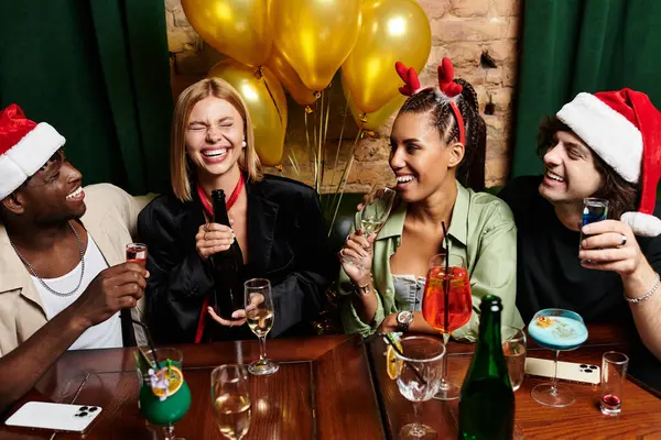 Young professionals enjoy laughter and drinks during a lively holiday office celebration. — Stock Photo